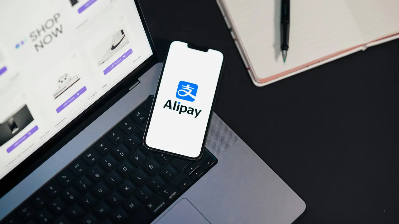 Phone displaying the Alipay logo on a laptop
