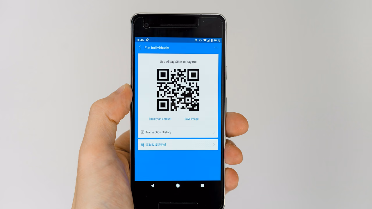 Hand met een telefoon waarop een Alipay-betaalcode staat