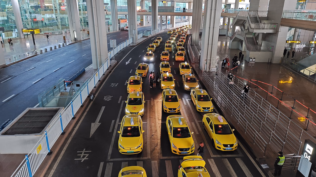 충칭 장베이 국제공항 T3의 정식 택시 승차장에 노란 택시들이 줄지어 서 있고 오른쪽에는 승객 대기 구역이 있습니다.
