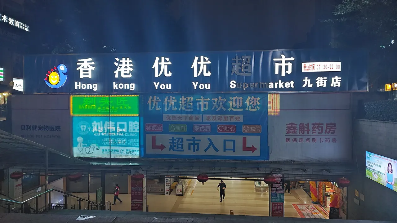 Supermarket entrance signs above steps leading below street level in Chongqing