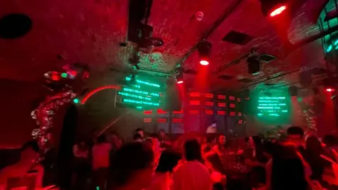 Guests under red lights and green screens inside Orangutan Bunker on 9th Street