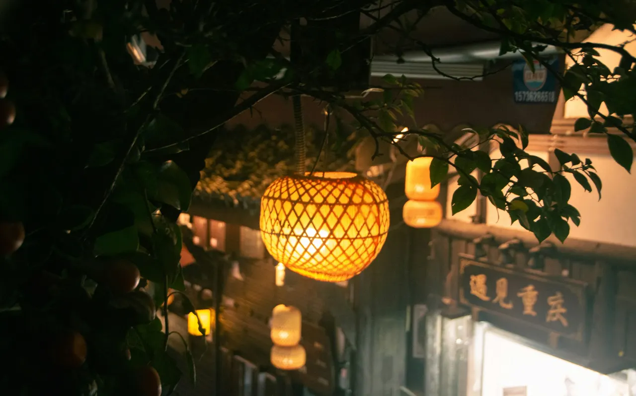 Warm woven lanterns glow among tree branches on a Chongqing street at night.