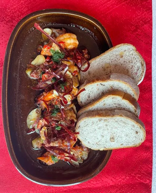 Gambas al ajo con verduras y rebanadas de pan en el restaurante Alma.