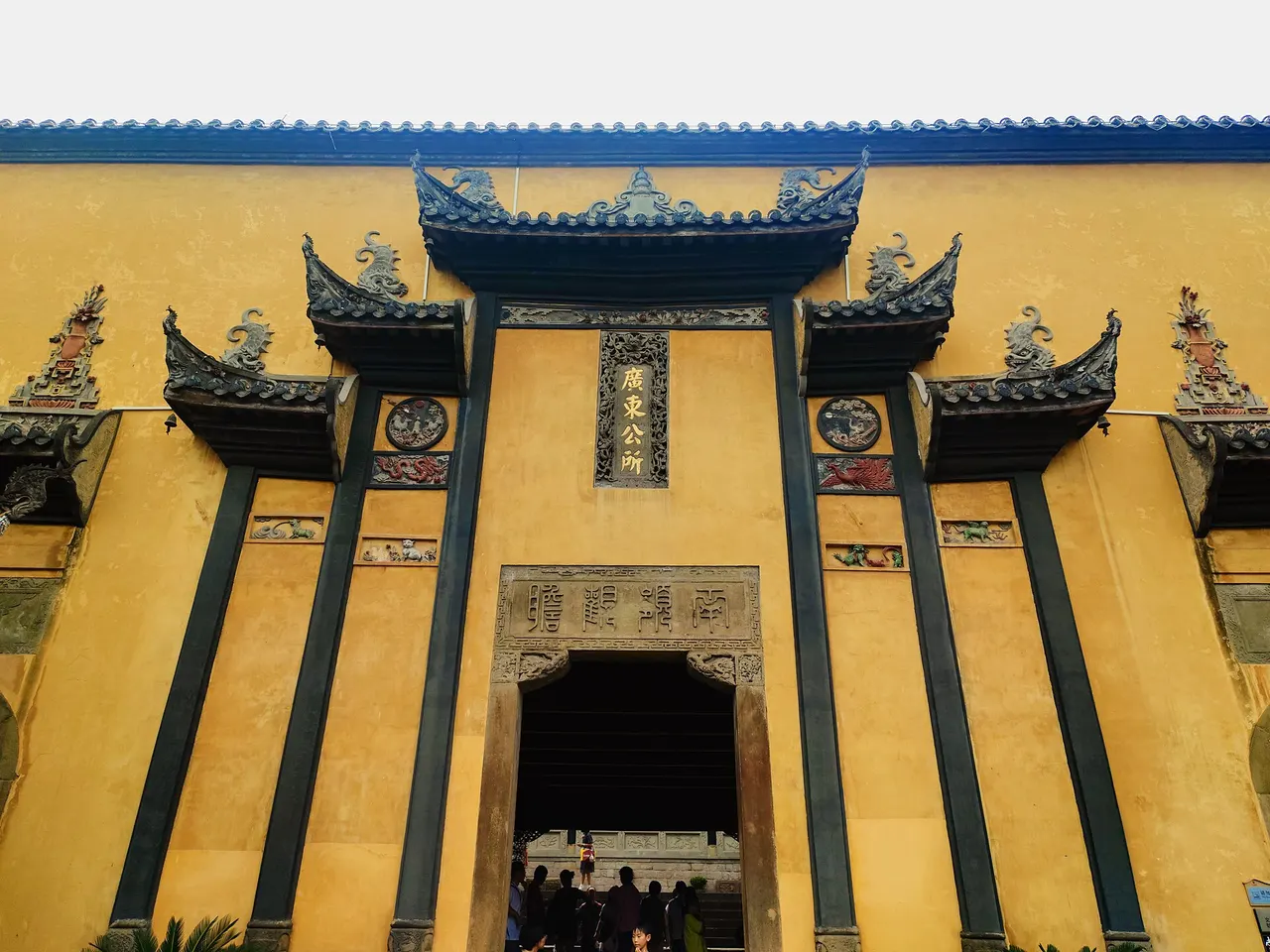Yellow walls and carved roof details at the Guangdong Association inside Chongqing's Huguang Guild Hall.