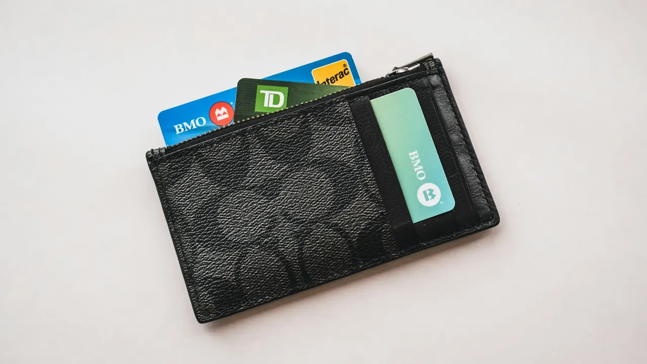 A dark wallet holding several payment cards on a light surface