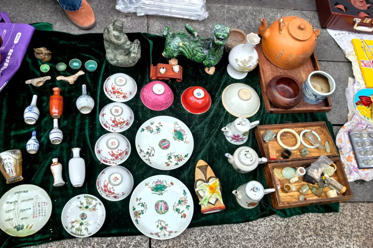 Ceramic plates, teapots and small old objects laid out on a stall on Zhongxing Road.