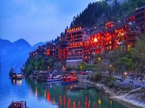 Riverside wooden buildings and boats at dusk in Gongtan