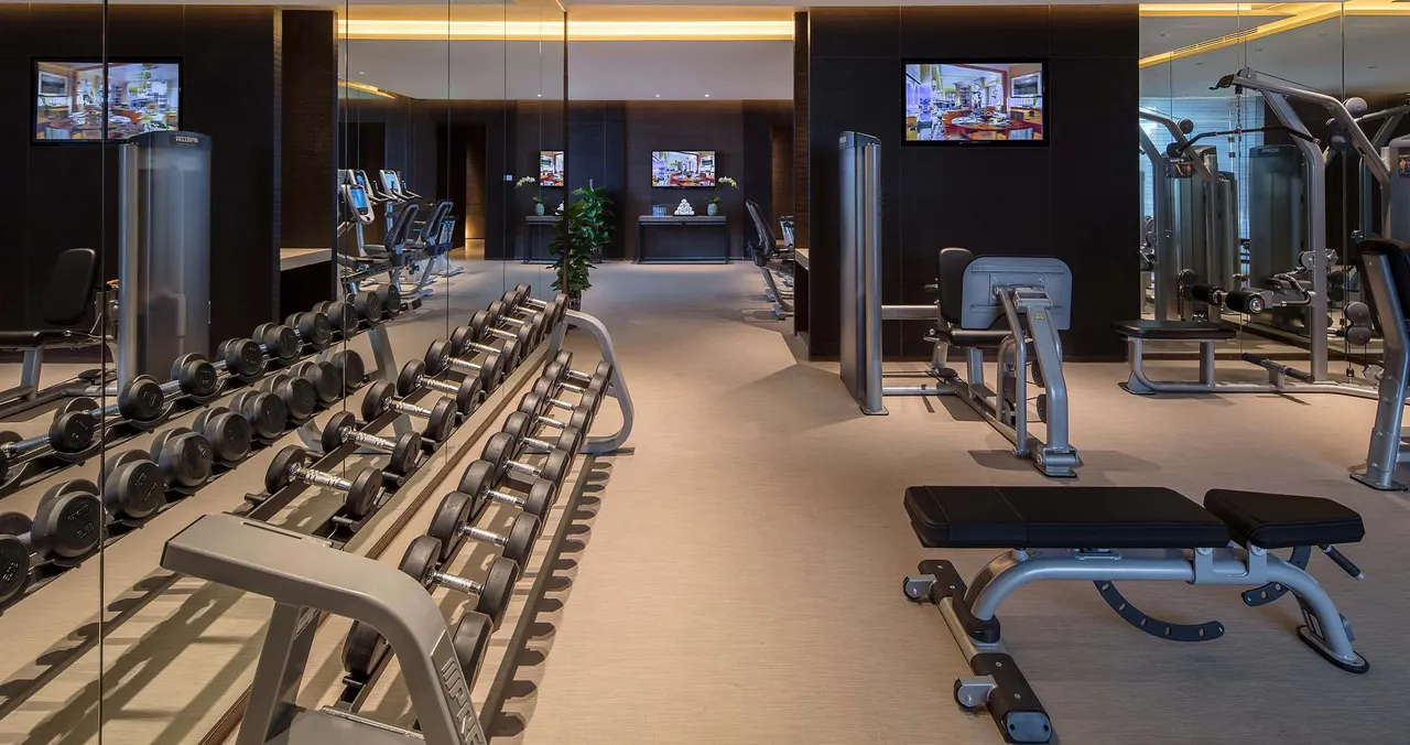 Dumbbell racks, an adjustable bench and strength machines in Regent Chongqing’s warm-lit gym