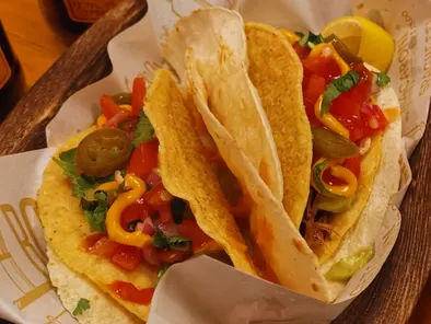 Dos tacos con tomate, hojas verdes y jalapeños, servidos en Los Tacos.