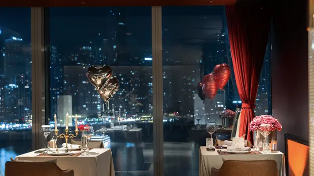 Tables près des fenêtres chez Diamond, avec la rivière et les lumières de Chongqing en arrière-plan.