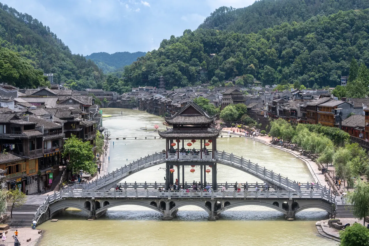 A pedestrian bridge over the Tuo River and riverside houses in Fenghuang