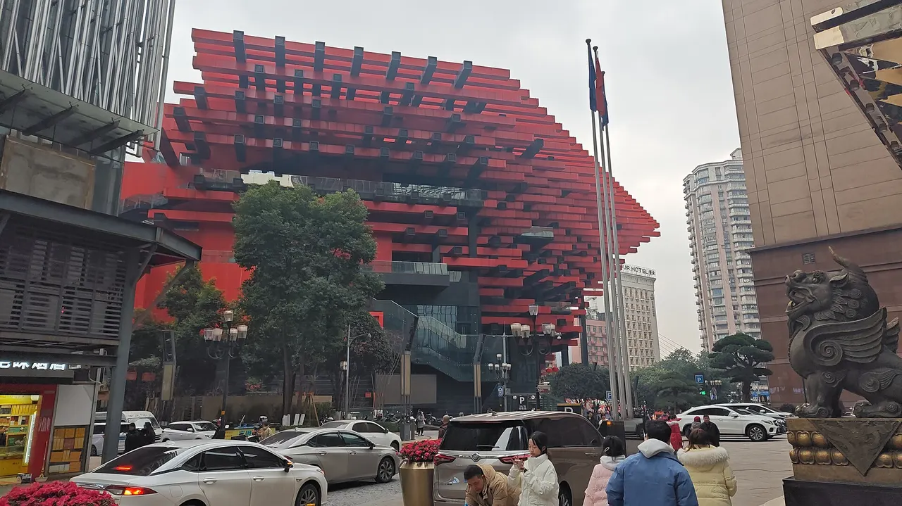 Chongqing Art Museum featuring its red and black beam exterior above a street corner.