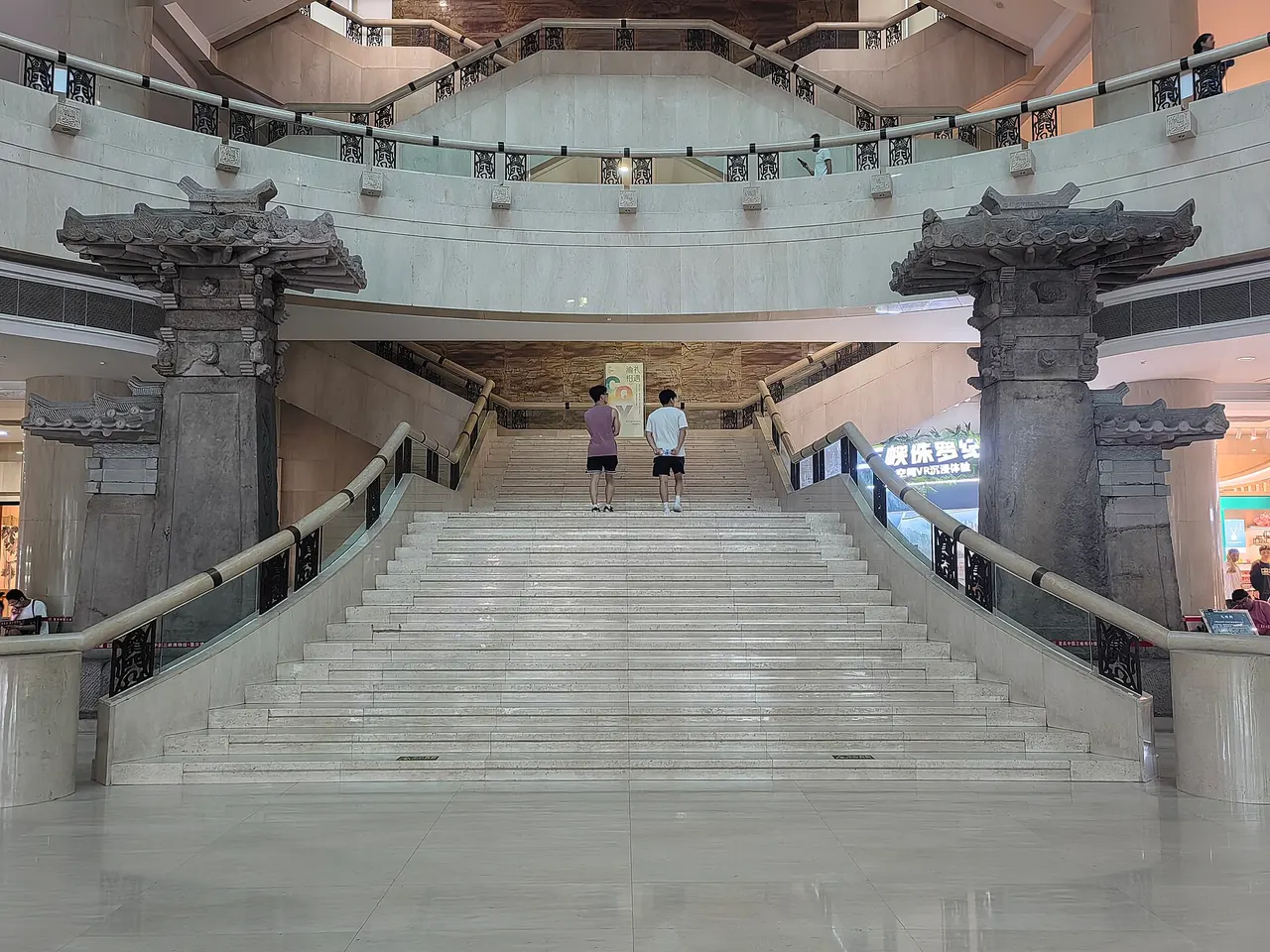 Ancient stone gate towers displayed beside an indoor museum staircase.