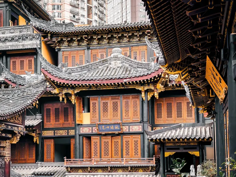 Carved wooden buildings and tiled eaves in Luohan Temple, with high-rise apartments behind