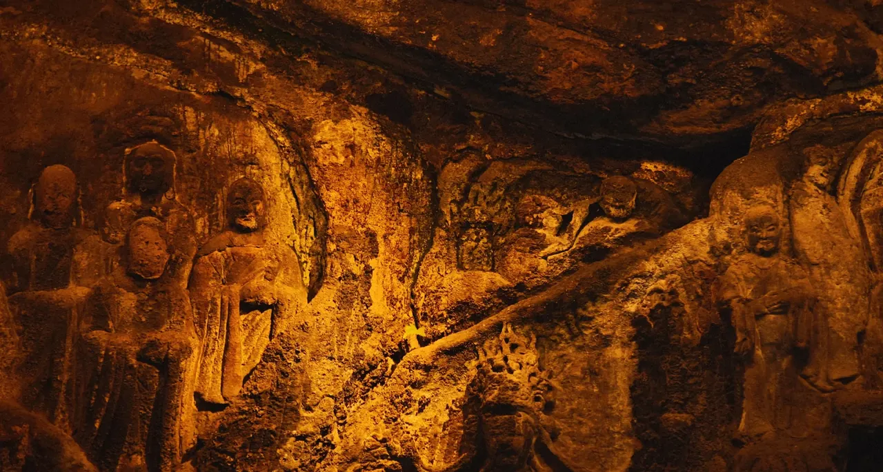 Standing stone figures and textured rock carvings at Gufoyan in Luohan Temple, lit by warm side light