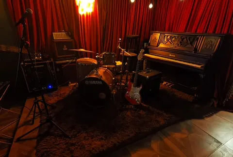 Piano and drum kit in front of red curtains at BB FUNK Jazz Club