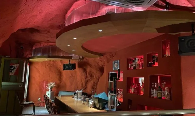 CAVER’s counter and seats beneath a red-lit rock ceiling
