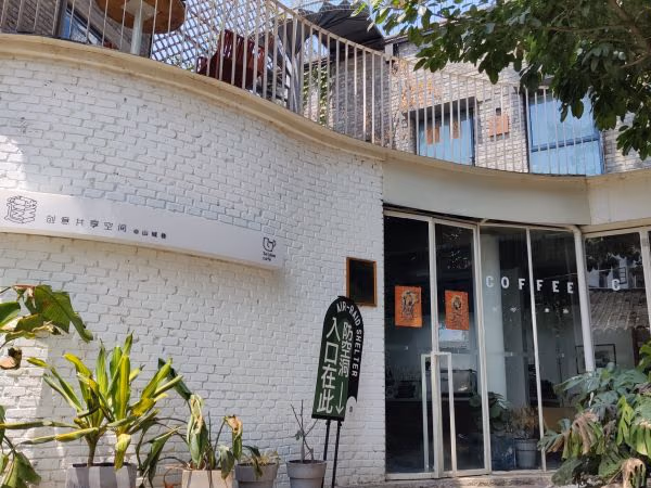 산청샹 Seldom 카페의 흰 벽돌 외벽과 간판, 유리 출입문.