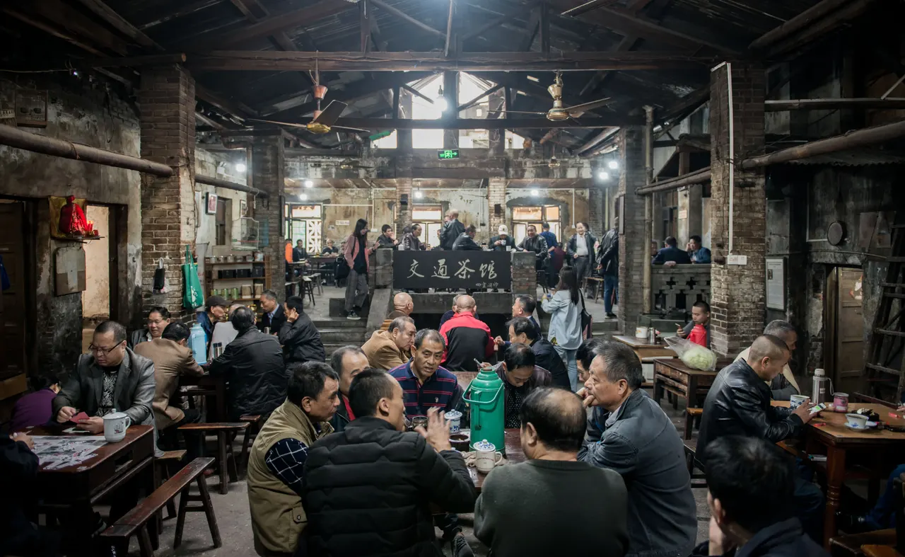 Visitors share tea tables beneath the wooden roof of Jiaotong Teahouse