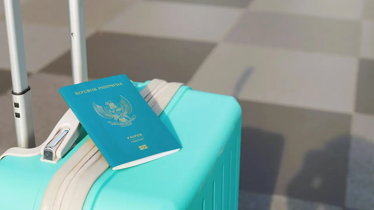 Paspor Indonesia di atas koper berwarna biru kehijauan di bandara