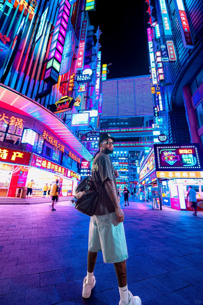 Man standing among blue and pink neon signs in Deyi World at night
