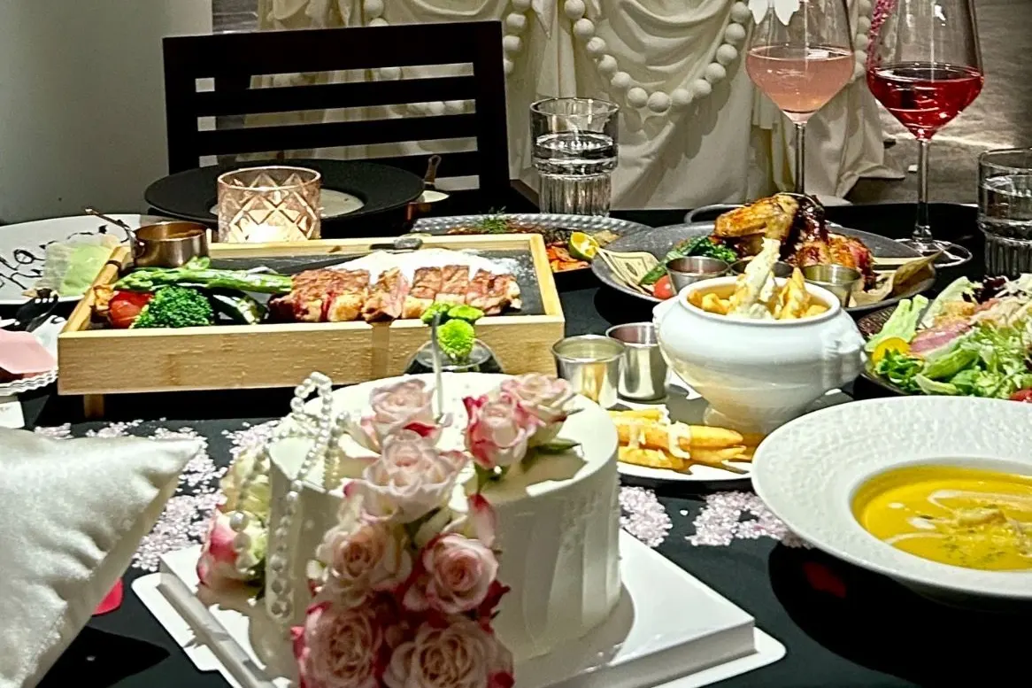 Mesa no BESO de Raffles City com carne grelhada, frango, salada, sopa e bolo decorado.
