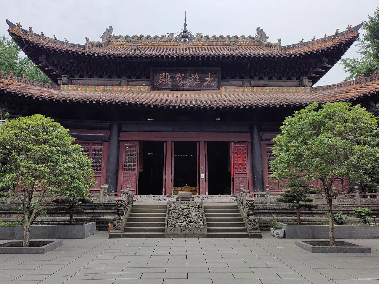 Baolun Temple in Ciqikou, with carved roof details, red doors and steps into the main hall.