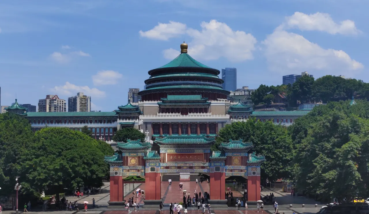 The green tiled dome and red entrance gates of Chongqing Great Hall of the People, seen across the square.