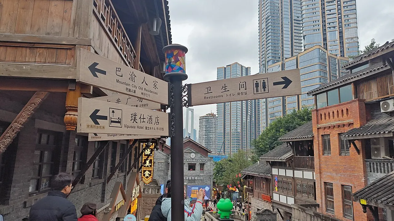 Multilingual directional signpost pointing toward stepped traditional streets and towers in Shibati.