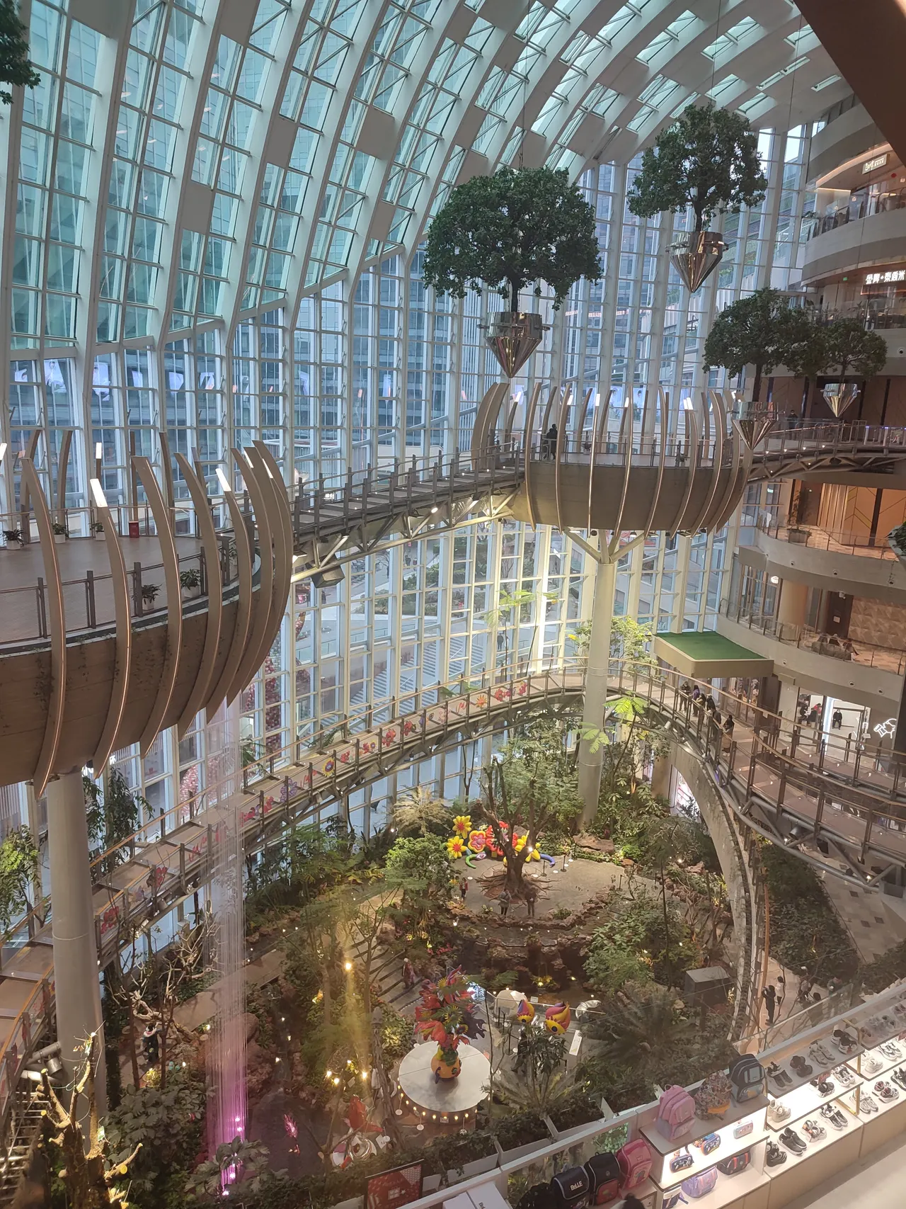Suspended trees and elevated walkways inside The Ring’s glass-covered botanical garden.