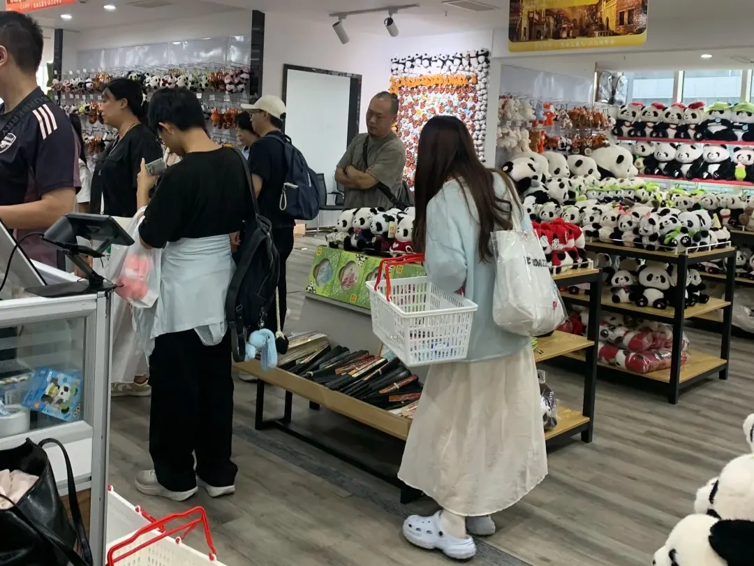 Shoppers beside shelves filled with panda toys inside the shop.