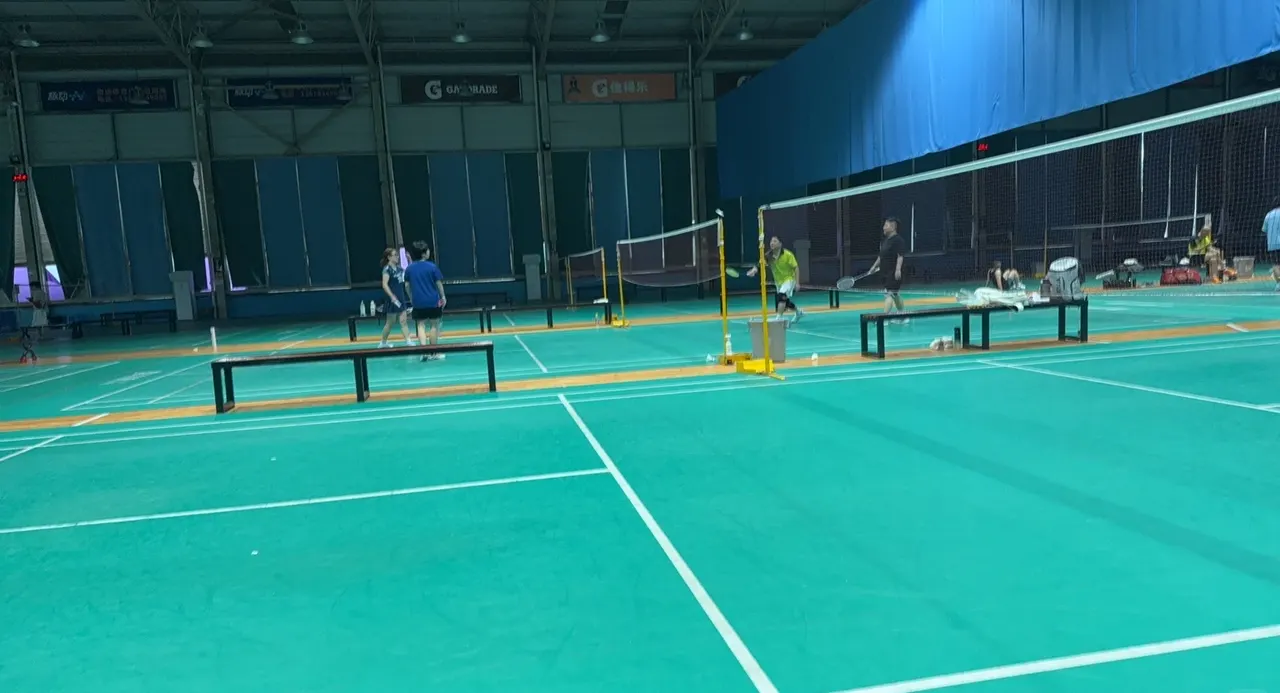 Players and nets on green indoor badminton courts at Chongqing Olympic Sports Center
