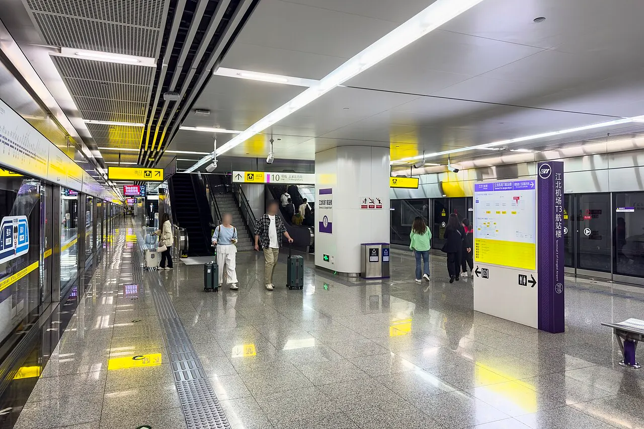 Subway platform at Jiangbei Airport Terminal 3 with screen doors and luggage-carrying travelers.