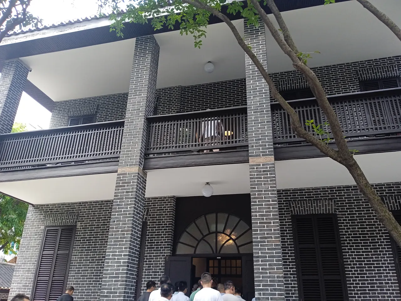 桂園主樓的灰磚柱、木欄杆陽台與拱形入口