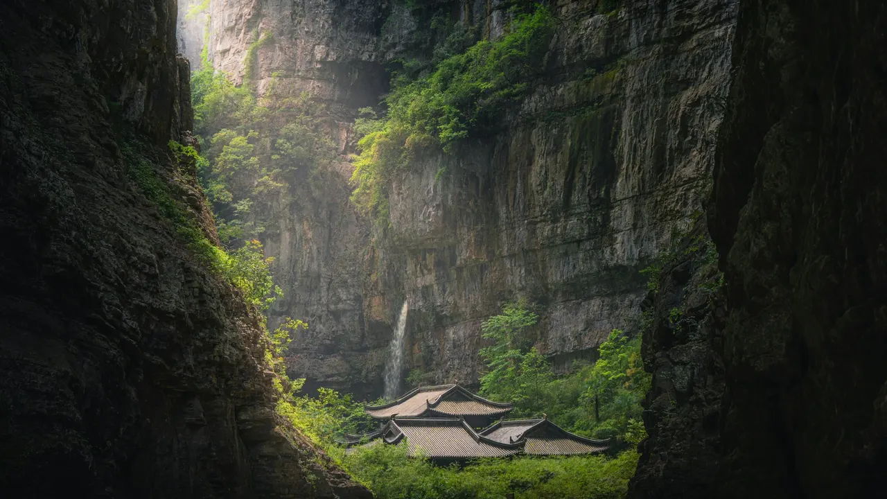 Tianfu post-house roofs below tall limestone cliffs in the Wulong canyon