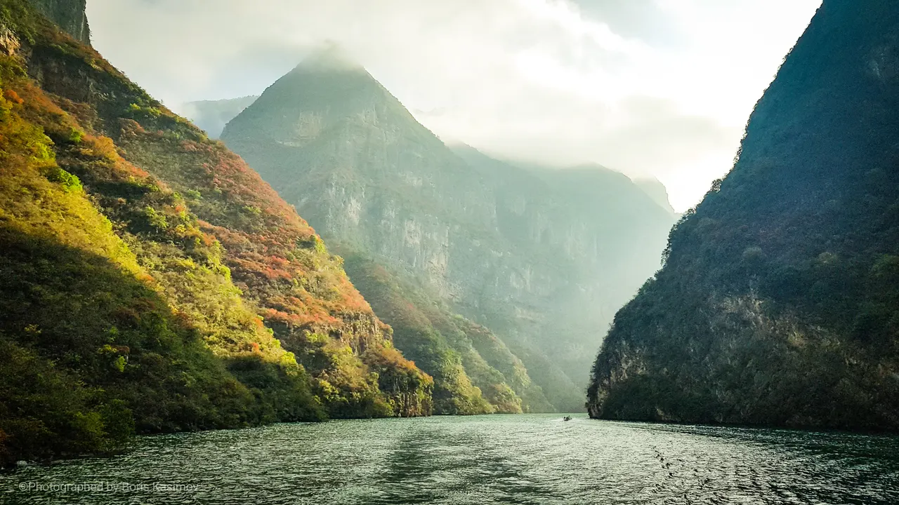 A river winds between green and golden cliffs in Chongqing's Three Gorges region.